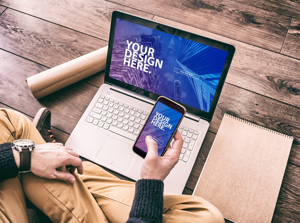 laptop-user-holding-smartphone-mockup-psd